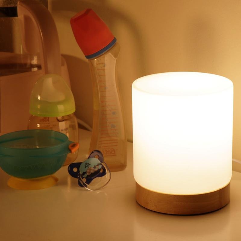 Baby bottle, pacifier, and night light on a surface with a warm glow.