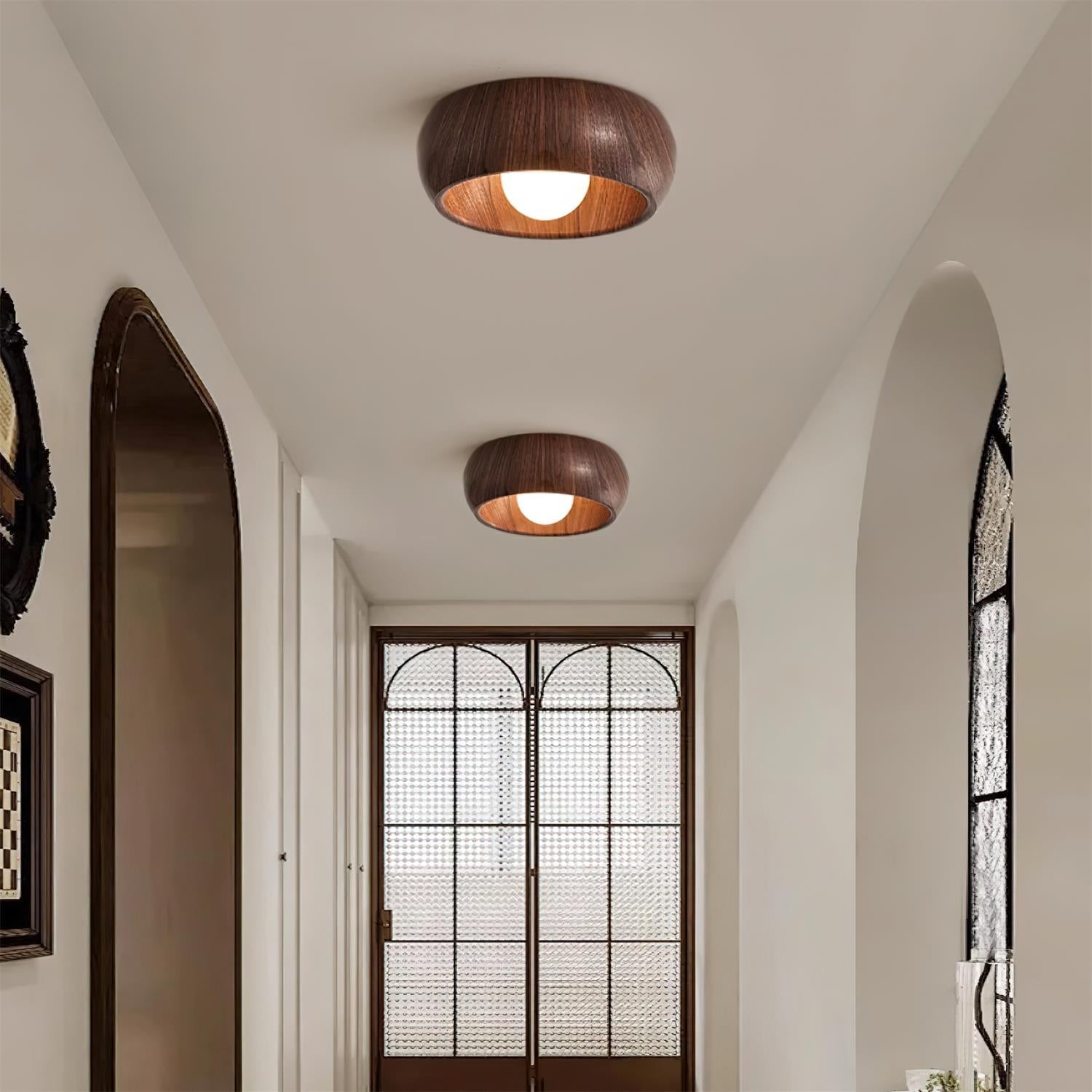 Two wooden ceiling lights in a room with a decorative door and window.