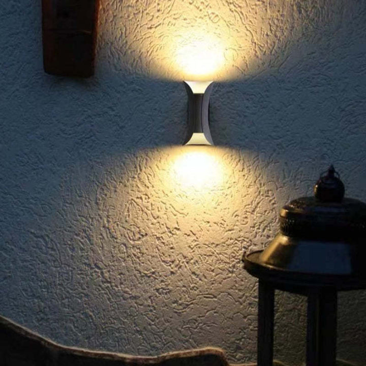 Wall-mounted light fixture casting a warm glow on a textured wall.