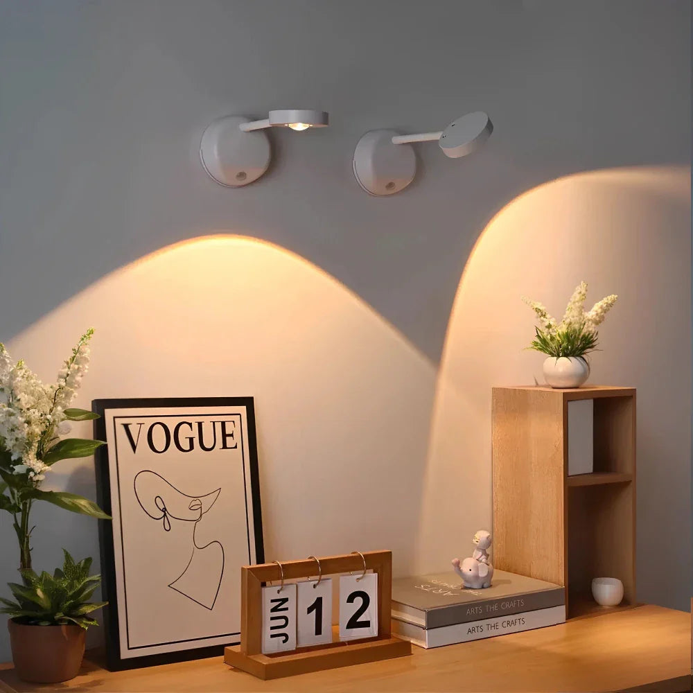 Decorative setup with a 'Vogue' magazine cover, calendar, and small books on a shelf against a wall with wall lights.