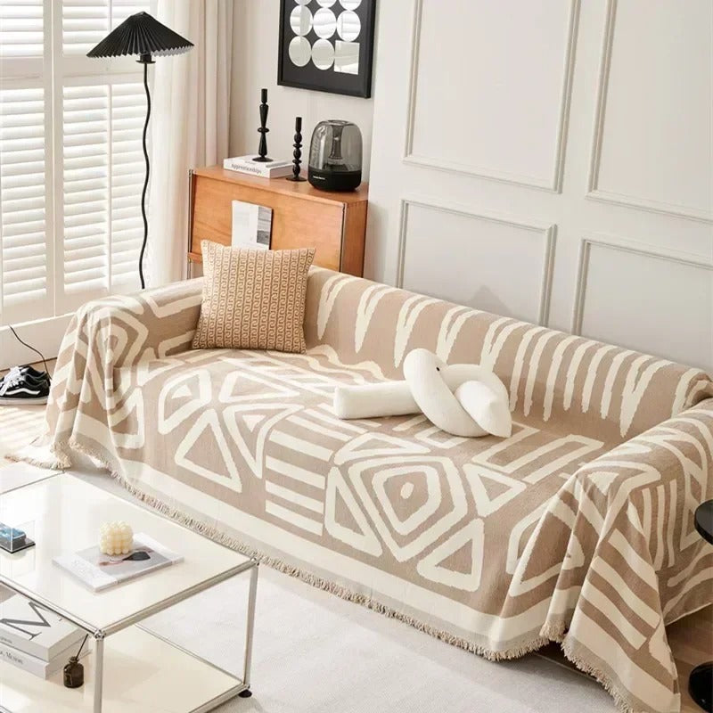 Beige and white patterned throw blanket on a sofa in a living room setting.