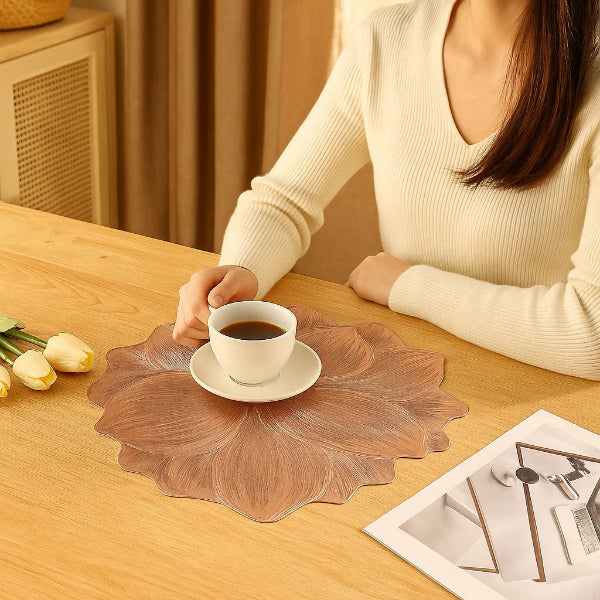 Person holding a cup of coffee on a decorative placemat with a magazine in the background.
