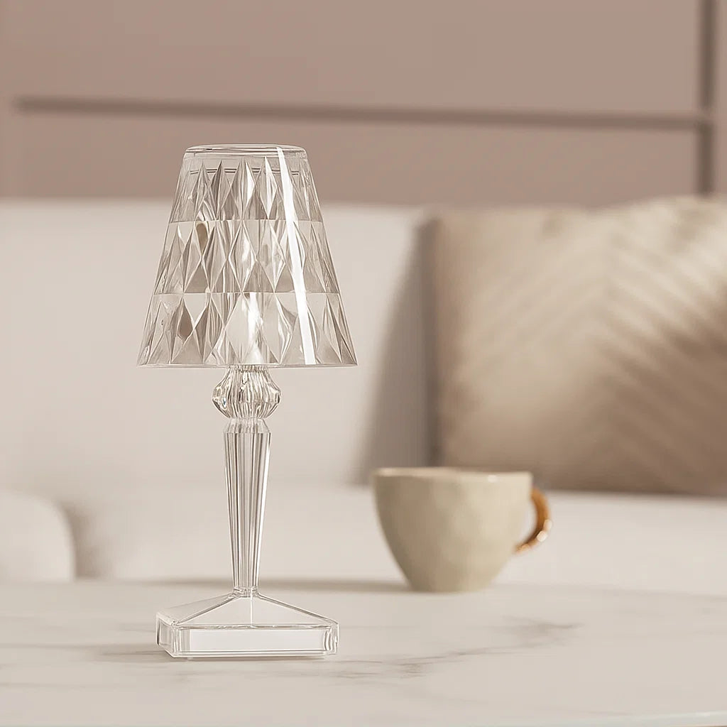 Clear glass table lamp on a surface with a blurred background