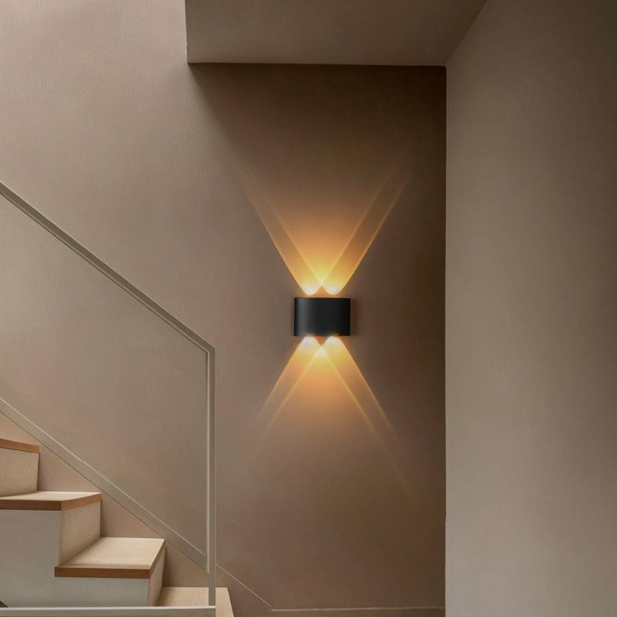 Modern wall-mounted light fixture casting a warm glow on a staircase wall.