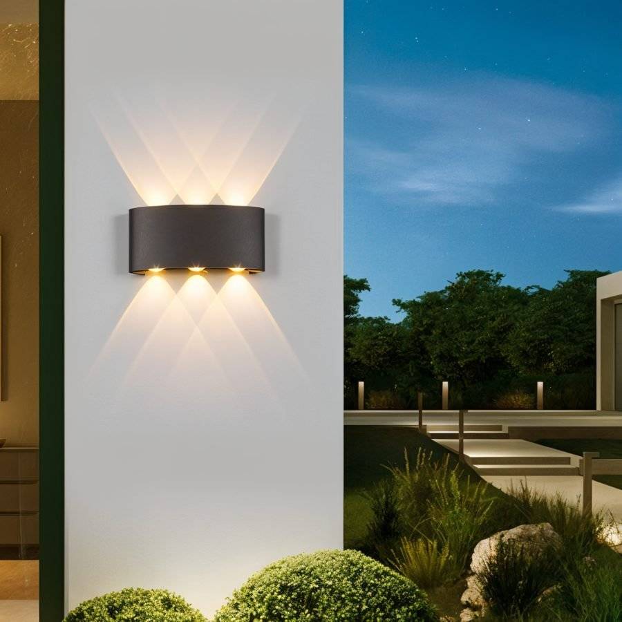 Modern outdoor wall light fixture on a building exterior with garden and sky in the background
