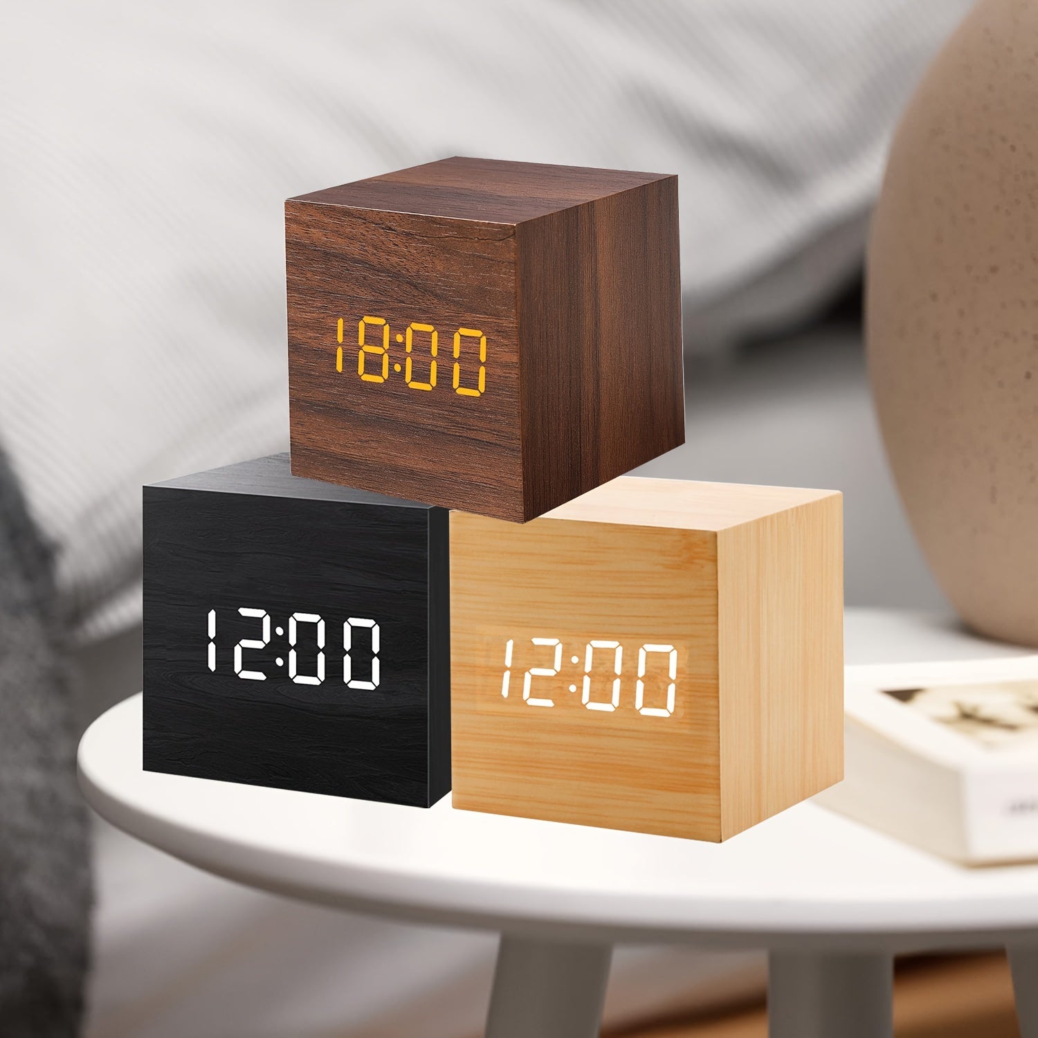 Three wooden digital clocks in different colors on a white surface.