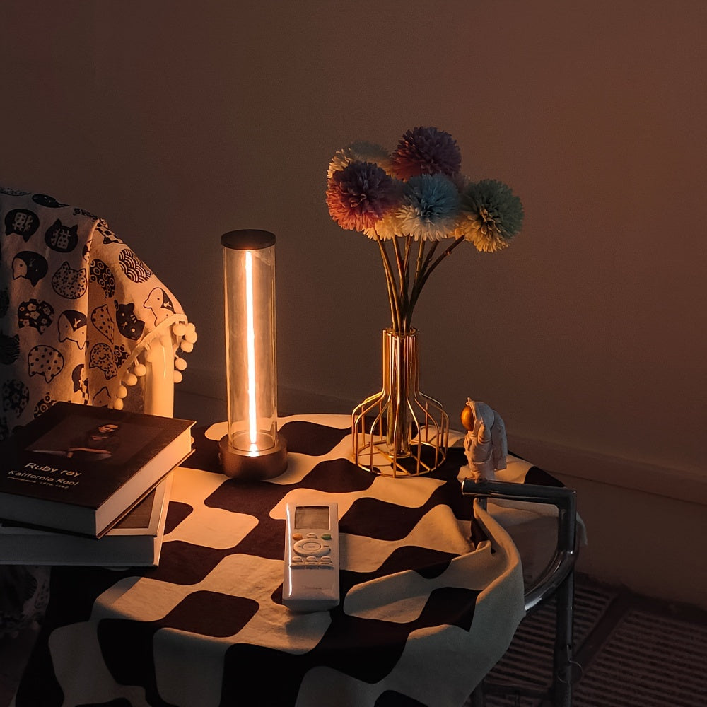 Small table with a lamp, vase of flowers, and books in a dimly lit room.