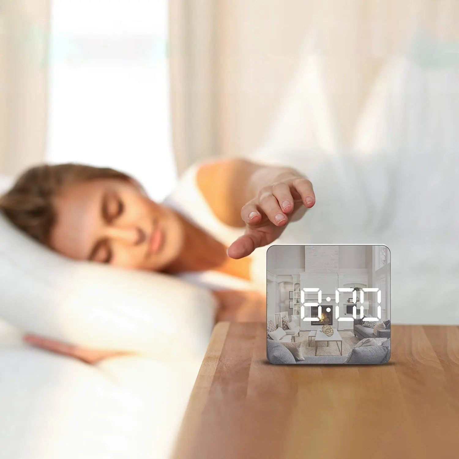Woman in bed with a digital clock showing the time on a wooden nightstand.