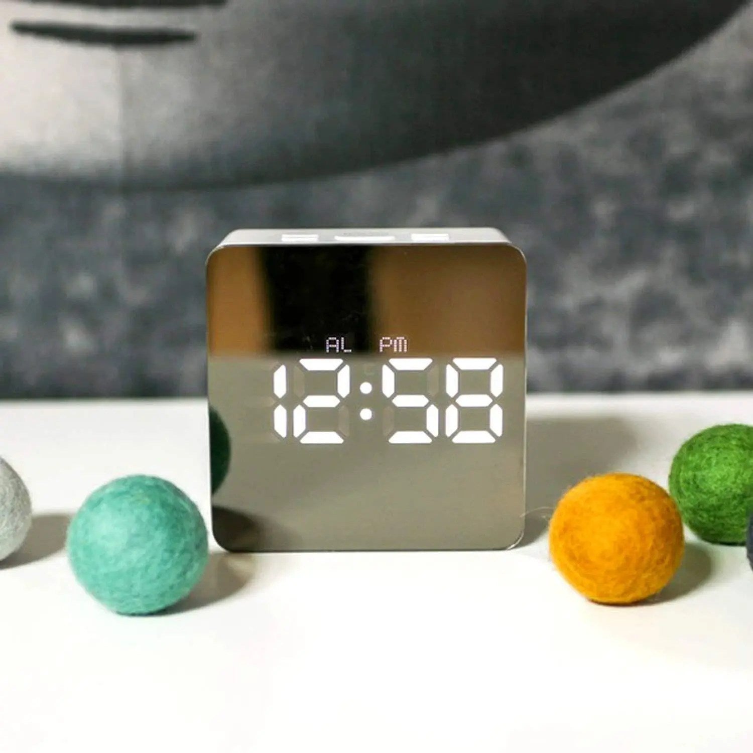 Digital clock with LED display on a surface with colorful balls
