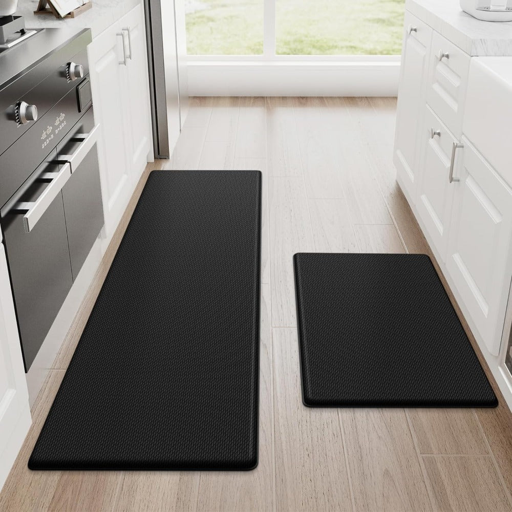 Two black kitchen mats on a wooden floor in a modern kitchen.