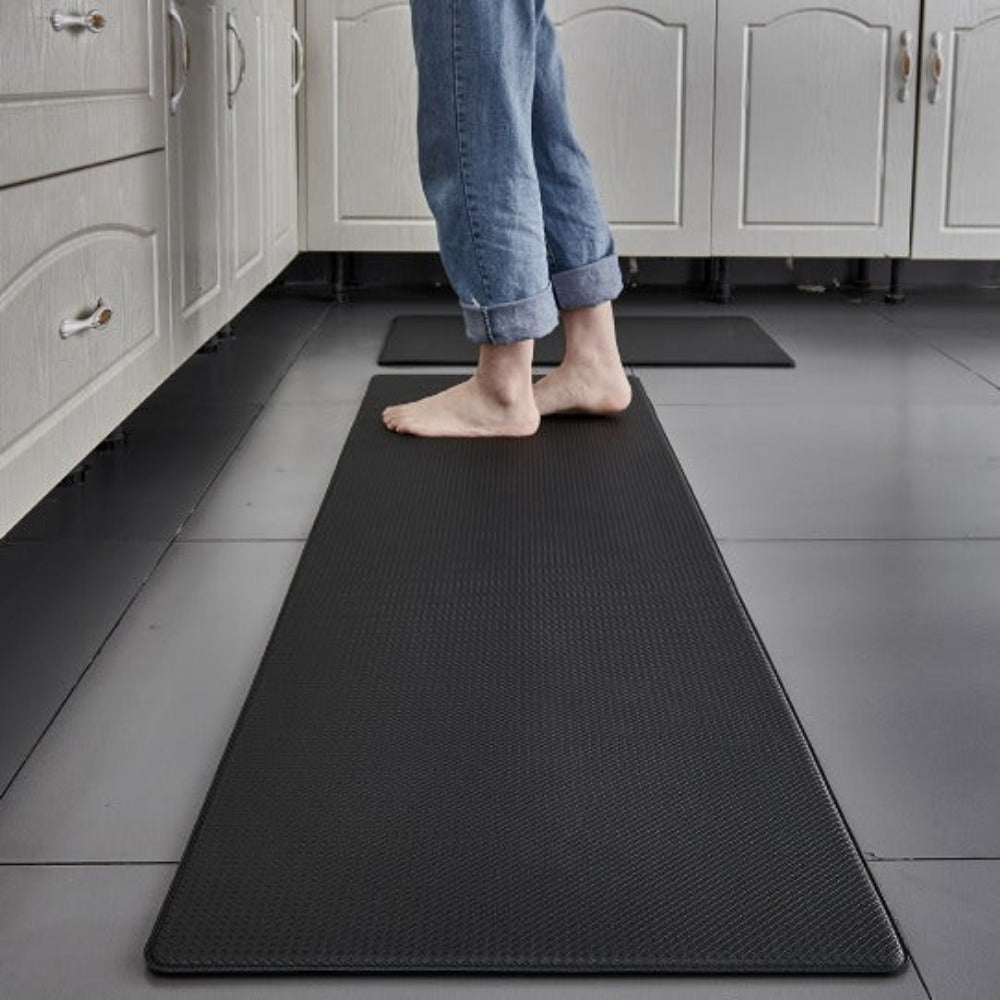 Person standing on a black anti-fatigue mat in a kitchen.