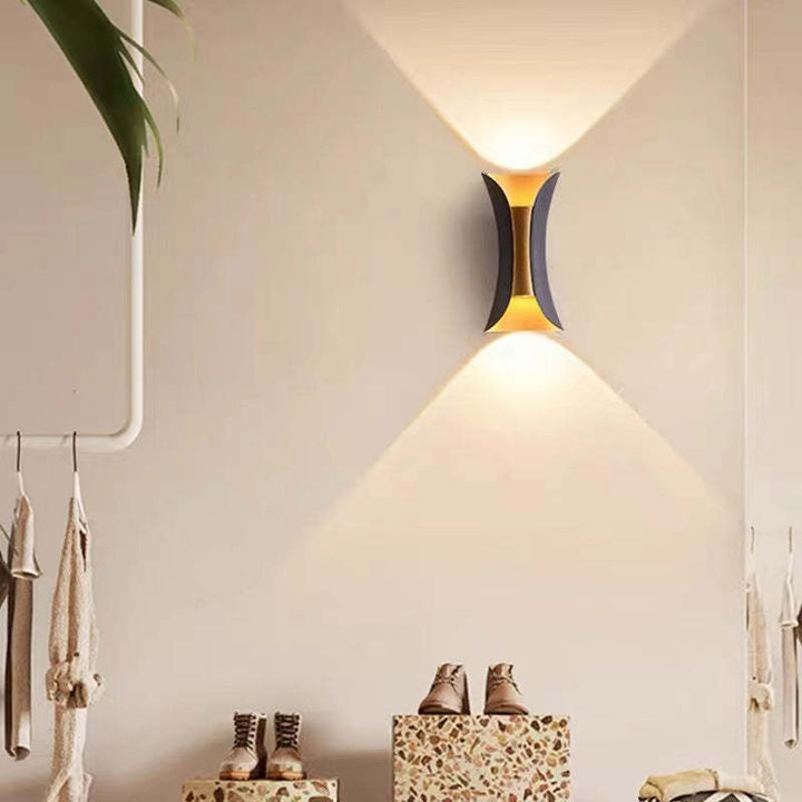 Wall-mounted lamp casting light on a wall with shoes and a plant in the background