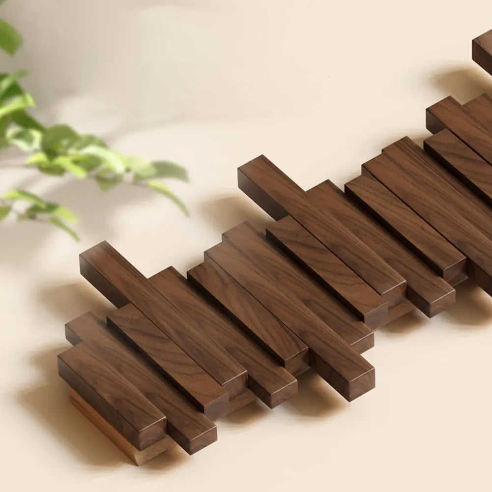 Wooden coasters arranged in a zigzag pattern on a light surface with a plant in the background.