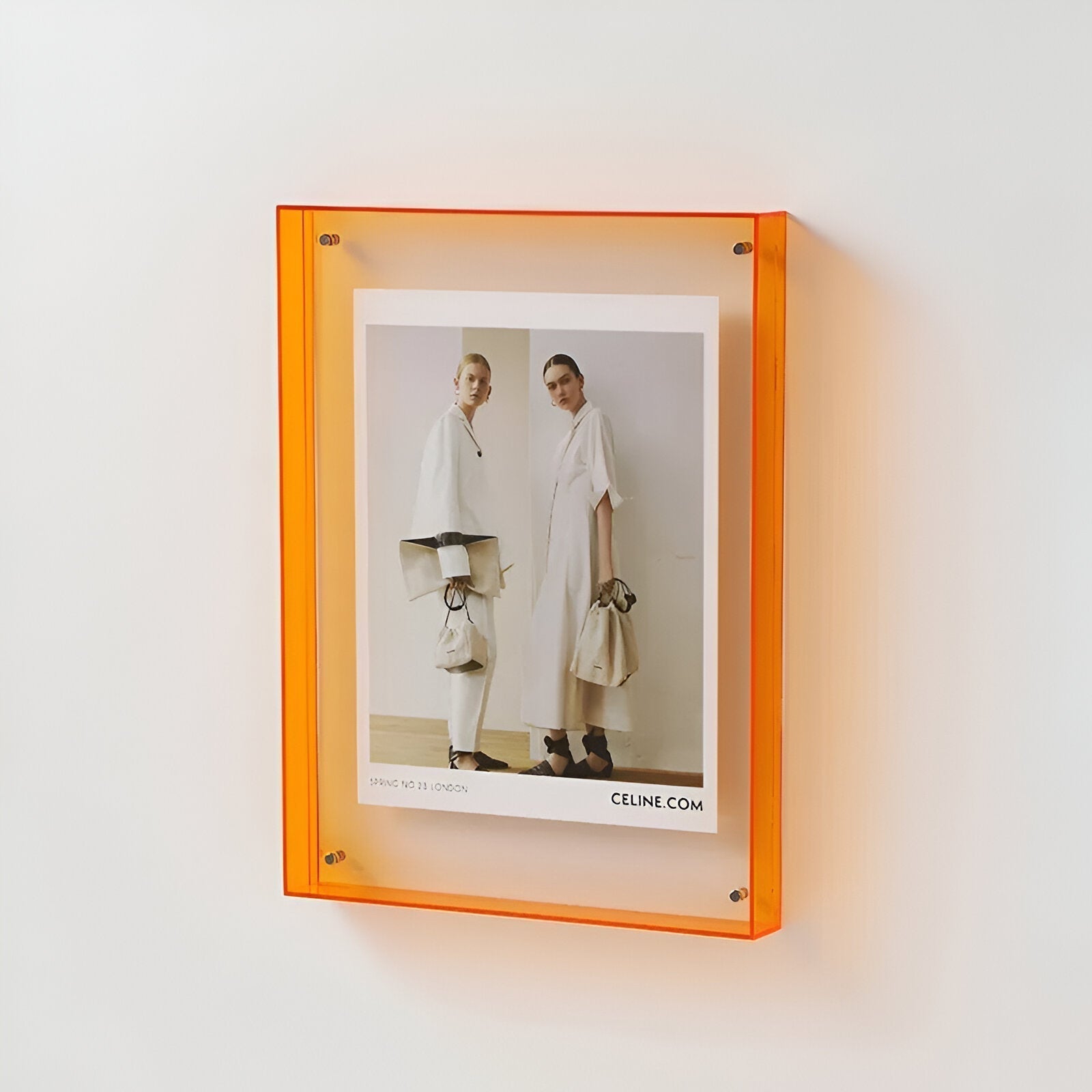 Orange frame with a Celine advertisement on a white wall