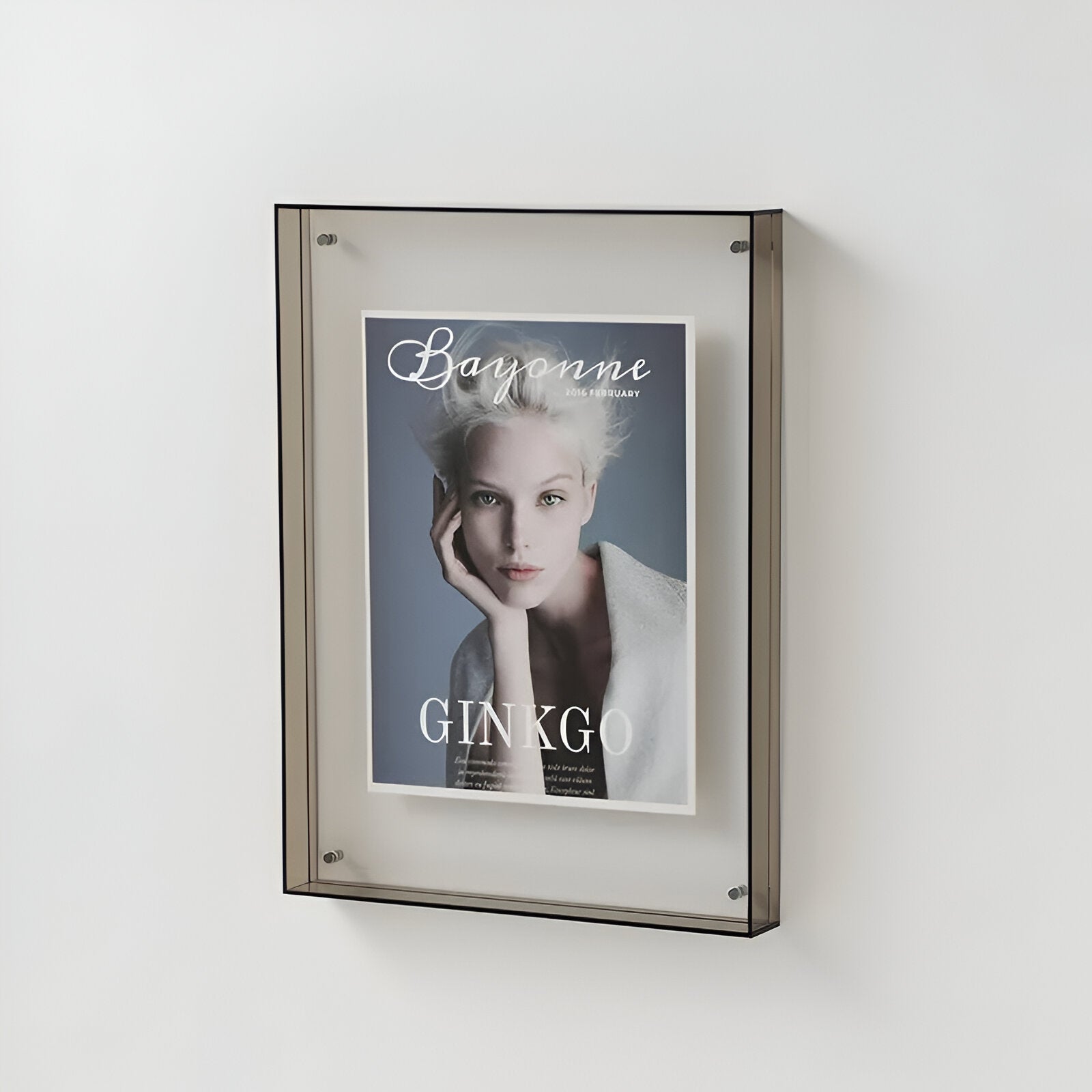 Framed magazine cover with a woman's face on a white wall