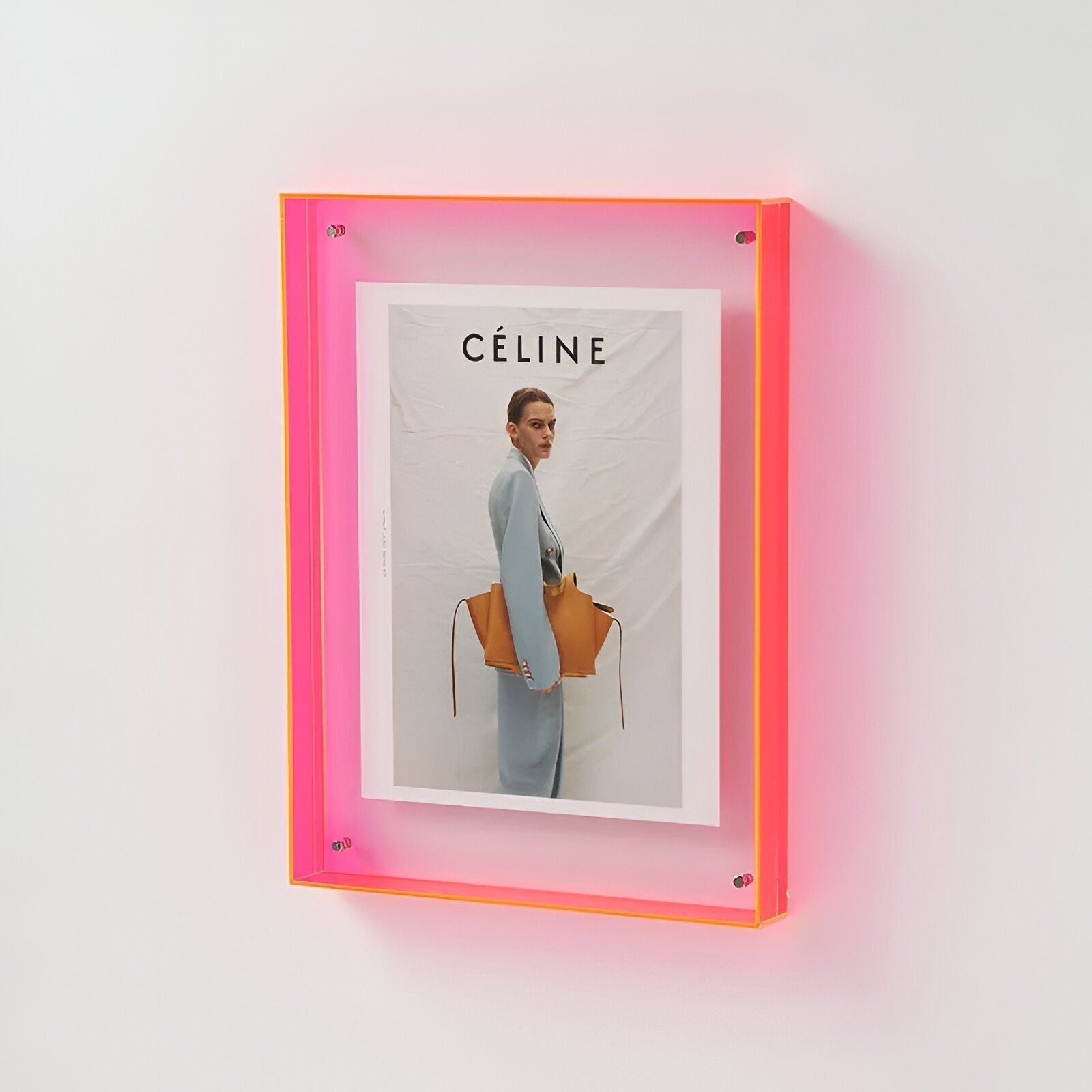 Céline advertisement with a woman holding a handbag in a neon pink frame.