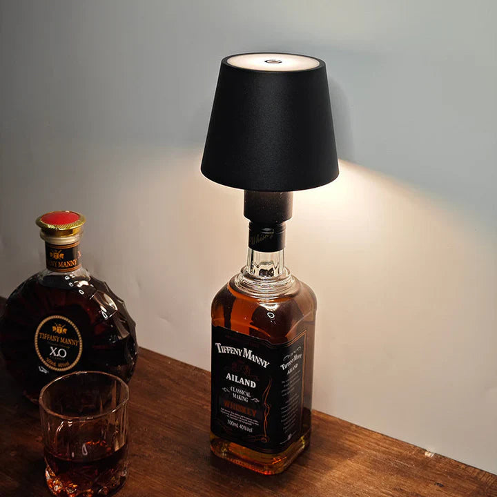  whiskey bottle repurposed as a lamp with a black shade on a wooden surface