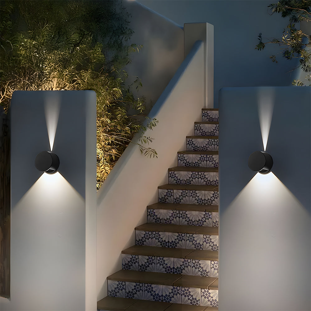 Staircase with decorative tiles illuminated by outdoor wall lights against a night sky.