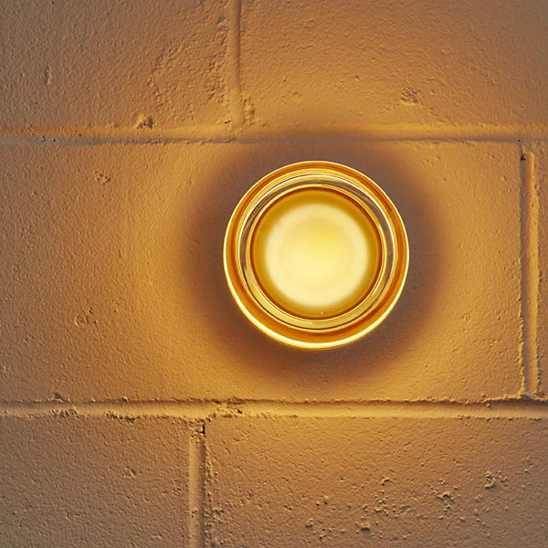 Round wall light fixture on a textured wall with warm color