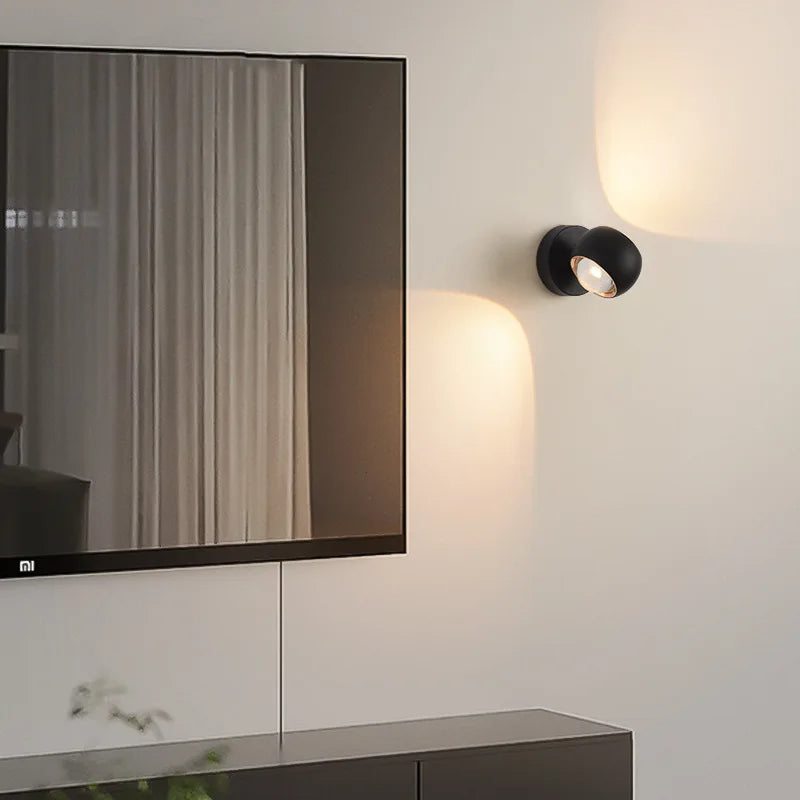 Modern wall-mounted light fixture next to a television screen on a white wall.