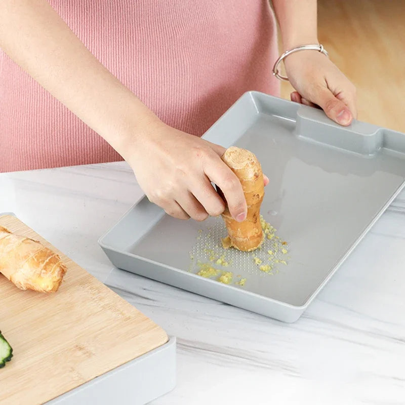Person preparing a pastry on a gray baking tray with a wooden cutting board and pink shirt in the background.