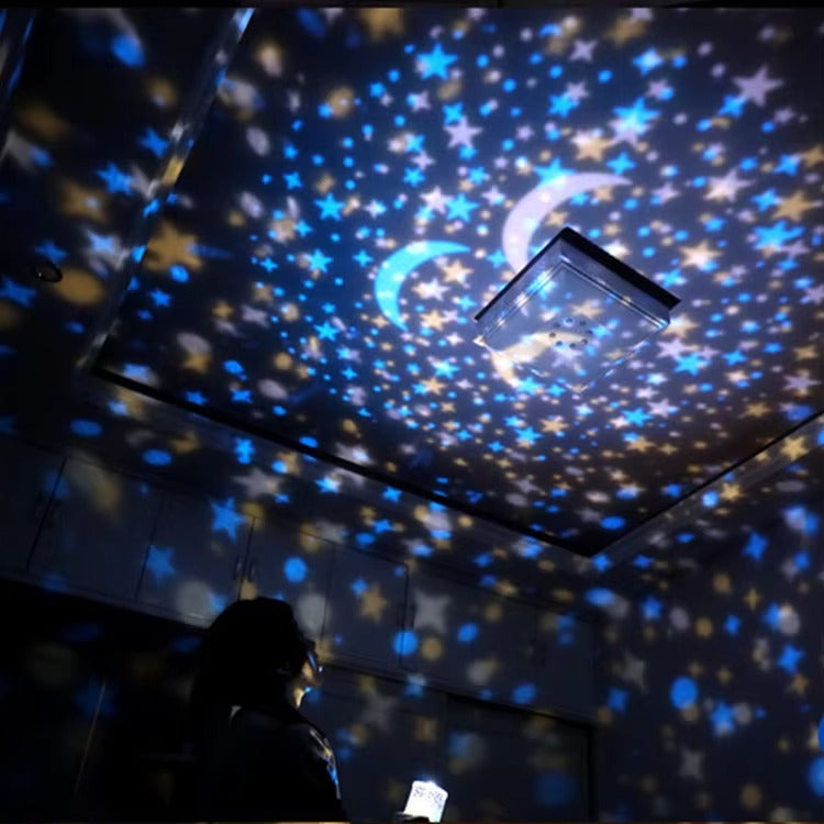 Ceiling with star and moon projections, person holding a phone in the foreground