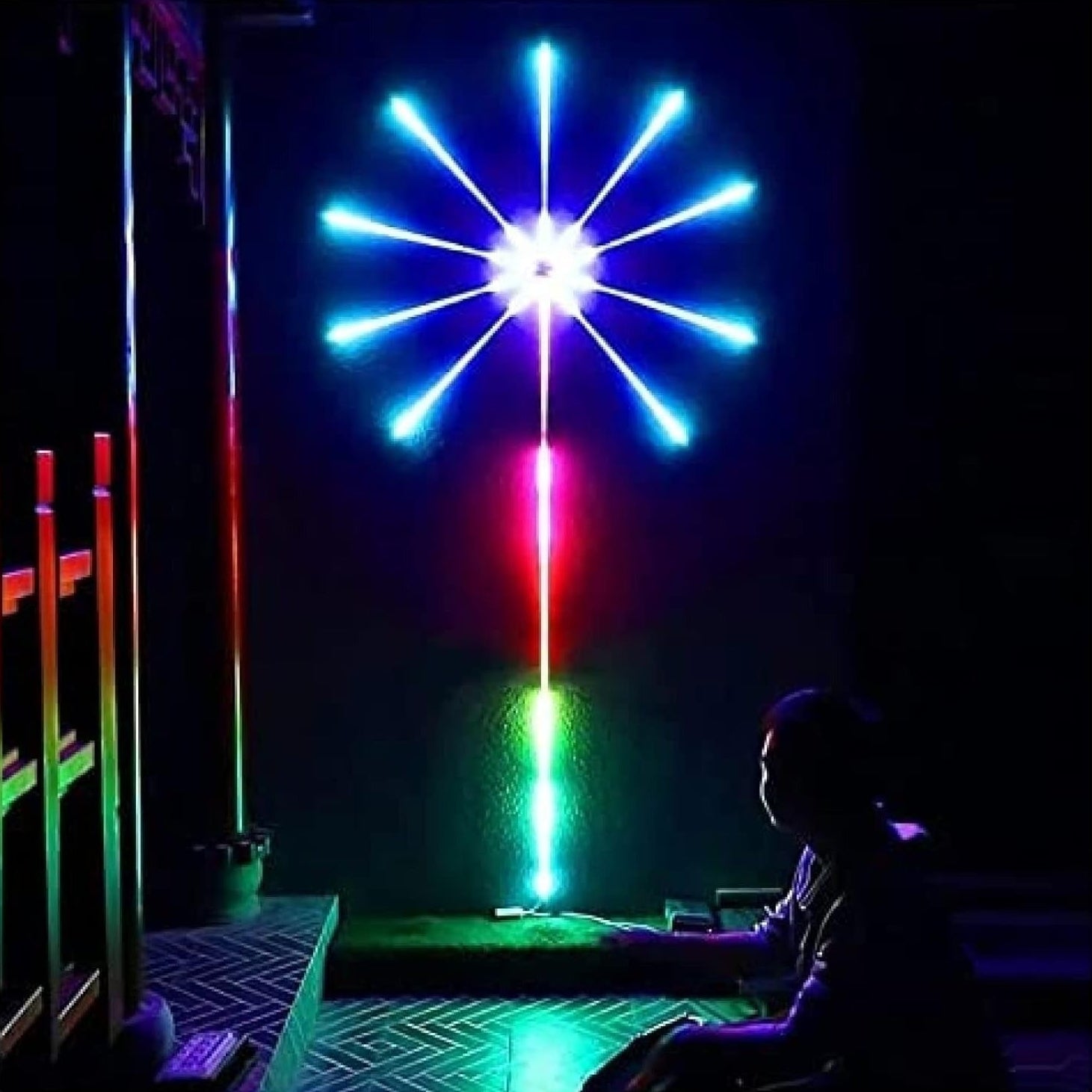Colorful LED light sculpture in a dark room with a person sitting nearby.