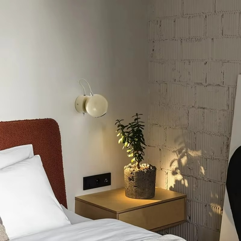 Bedroom with a nightstand, lamp, and plant against a textured wall.
