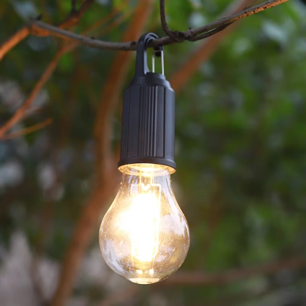 String light bulb hanging from a branch with a blurred green background