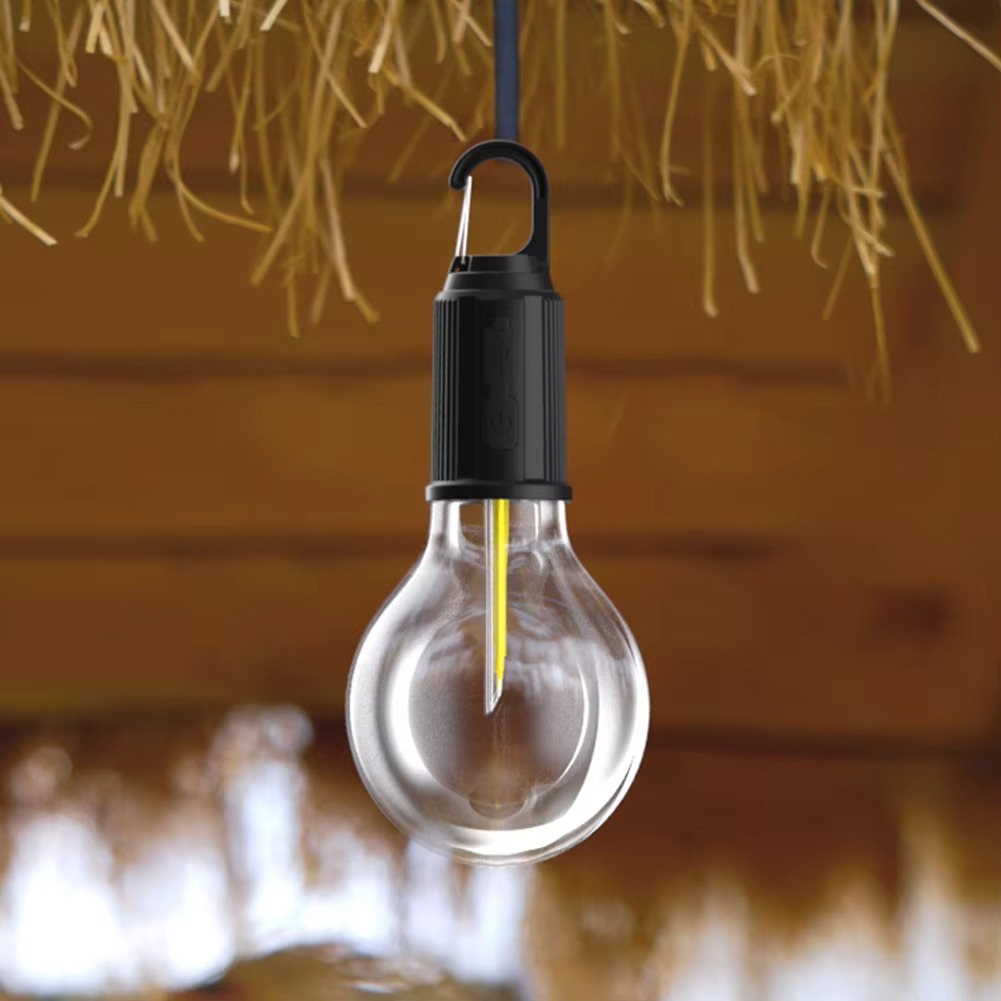 Clear light bulb with black base hanging against a rustic wooden background