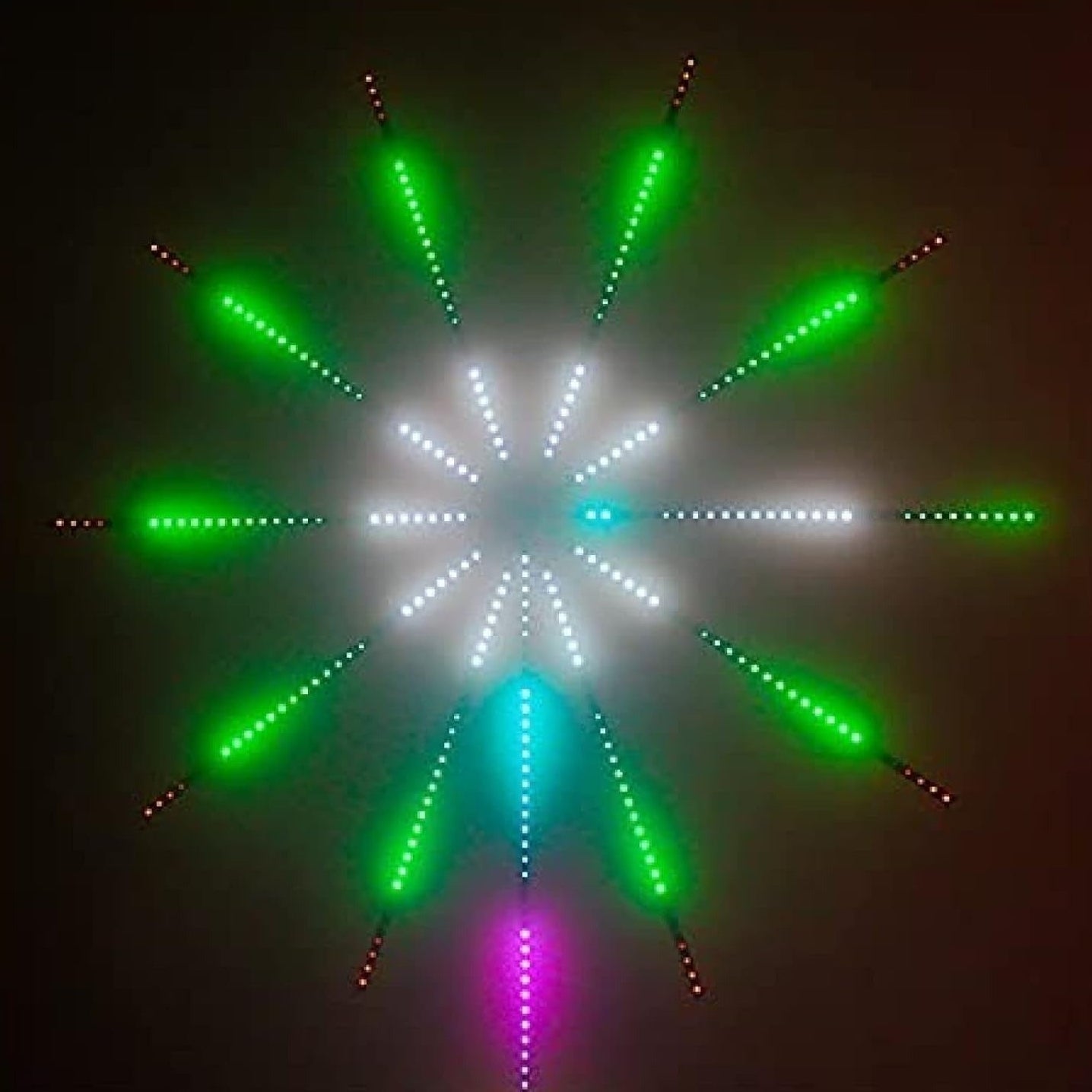 Star-shaped light display with green and white lights on a dark background