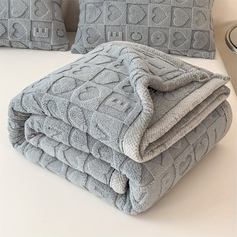 Gray textured blanket and pillows on a light-colored surface