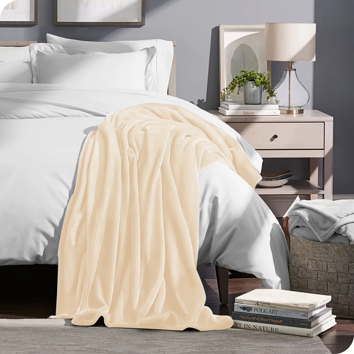 Beige blanket draped over a bed in a bedroom setting with a nightstand and lamp.