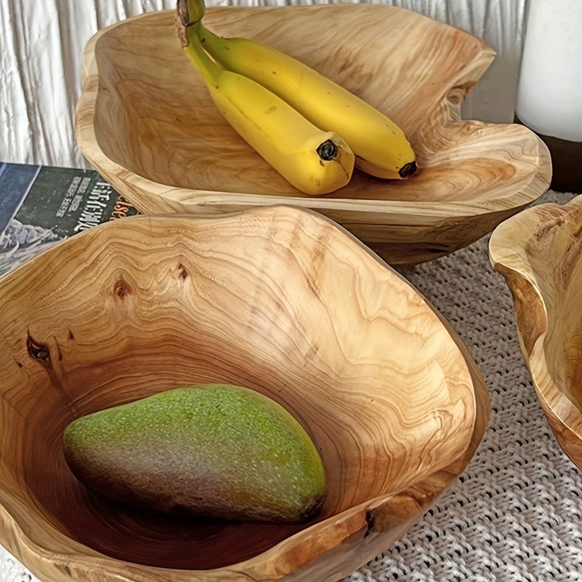 Wooden bowls with a mango and bananas on a textured surface