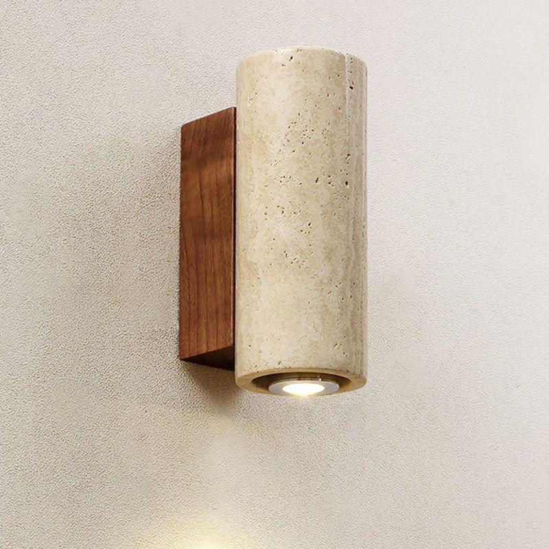 Wall-mounted outdoor light fixture with wooden base and beige cylindrical shade on a textured wall.