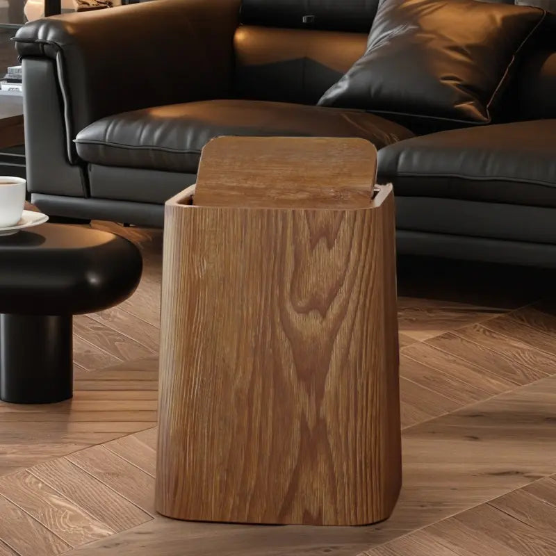 Wooden side table in a living room setting with a black leather sofa and coffee table.