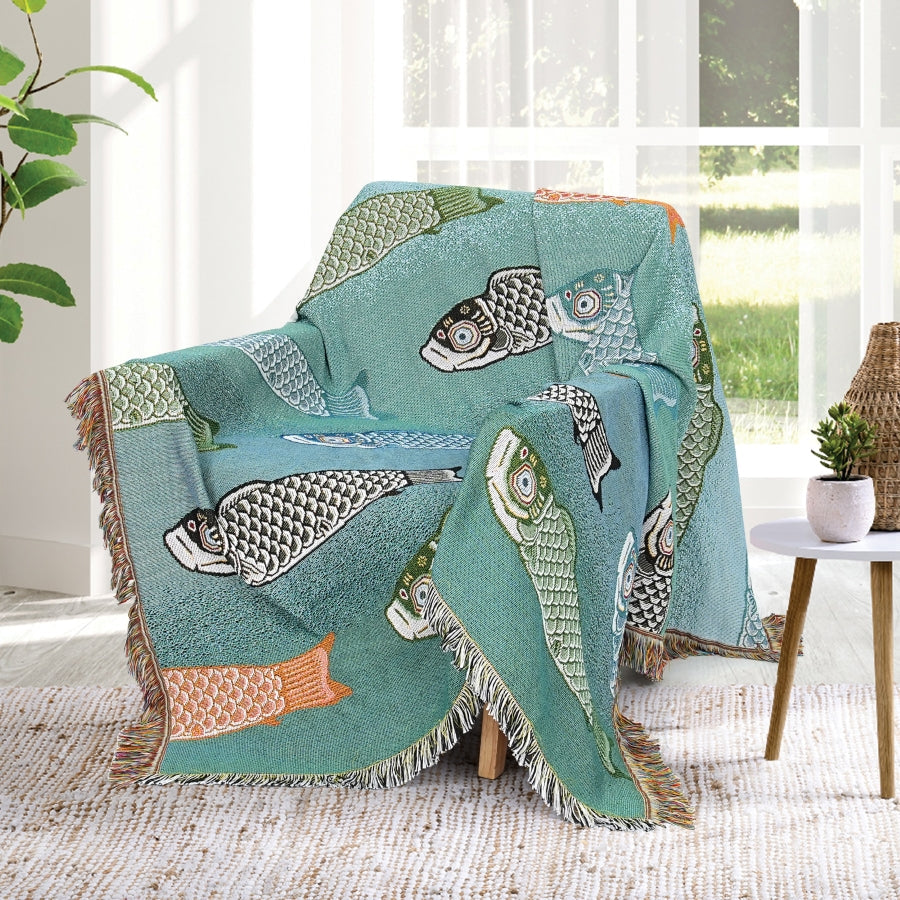 Fish-patterned blanket draped over a chair in a room with a window and plant.
