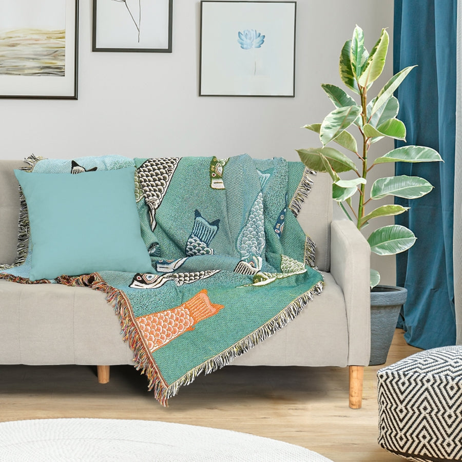 Decorative throw blanket with fish pattern on a sofa in a living room setting.