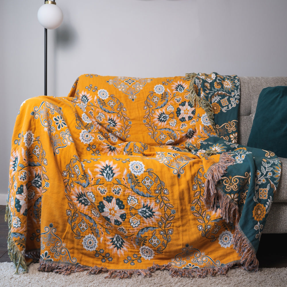 Decorative floral-patterned blanket draped over a sofa in a living room setting.