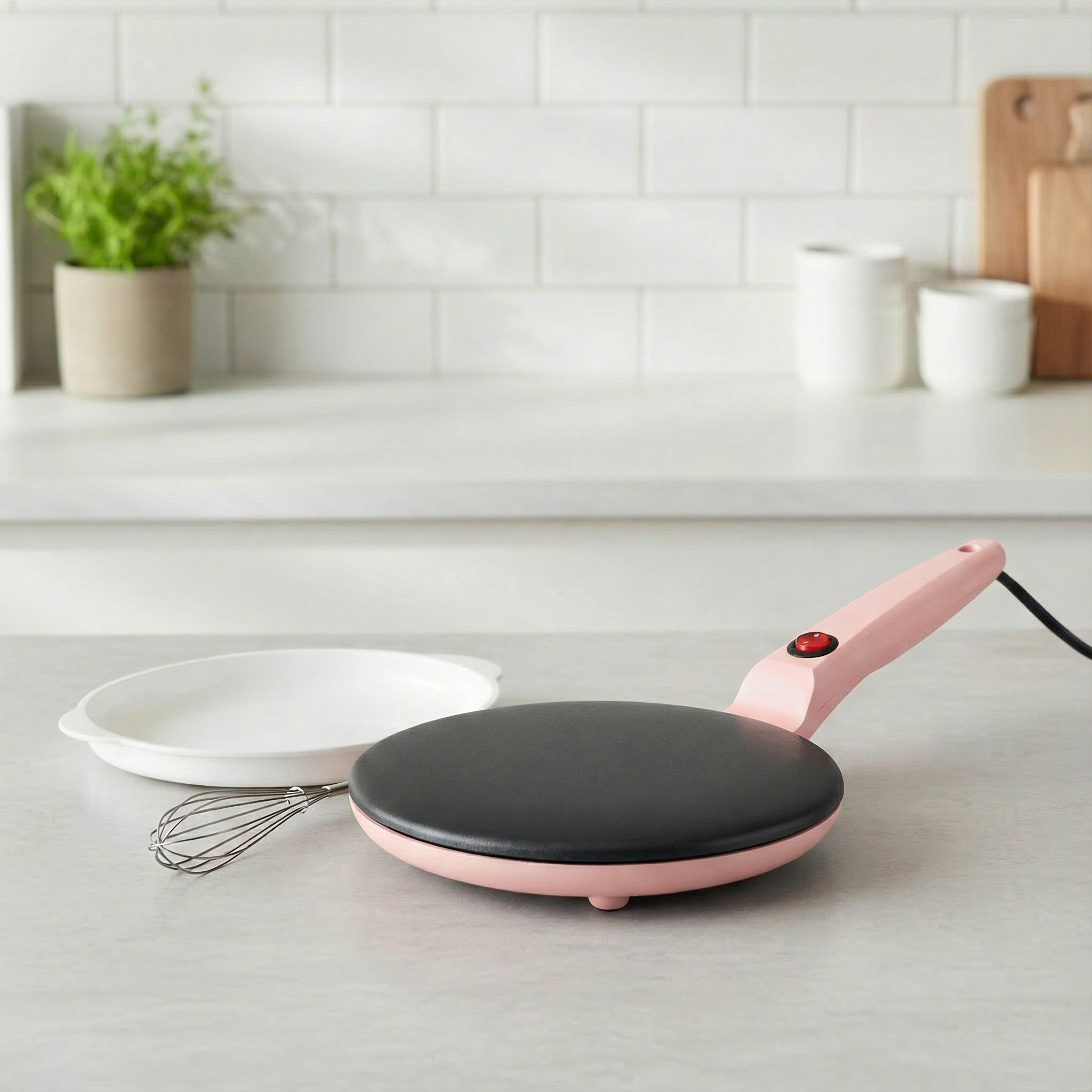 Pink electric crepe maker on a kitchen counter with a white tiled wall in the background.