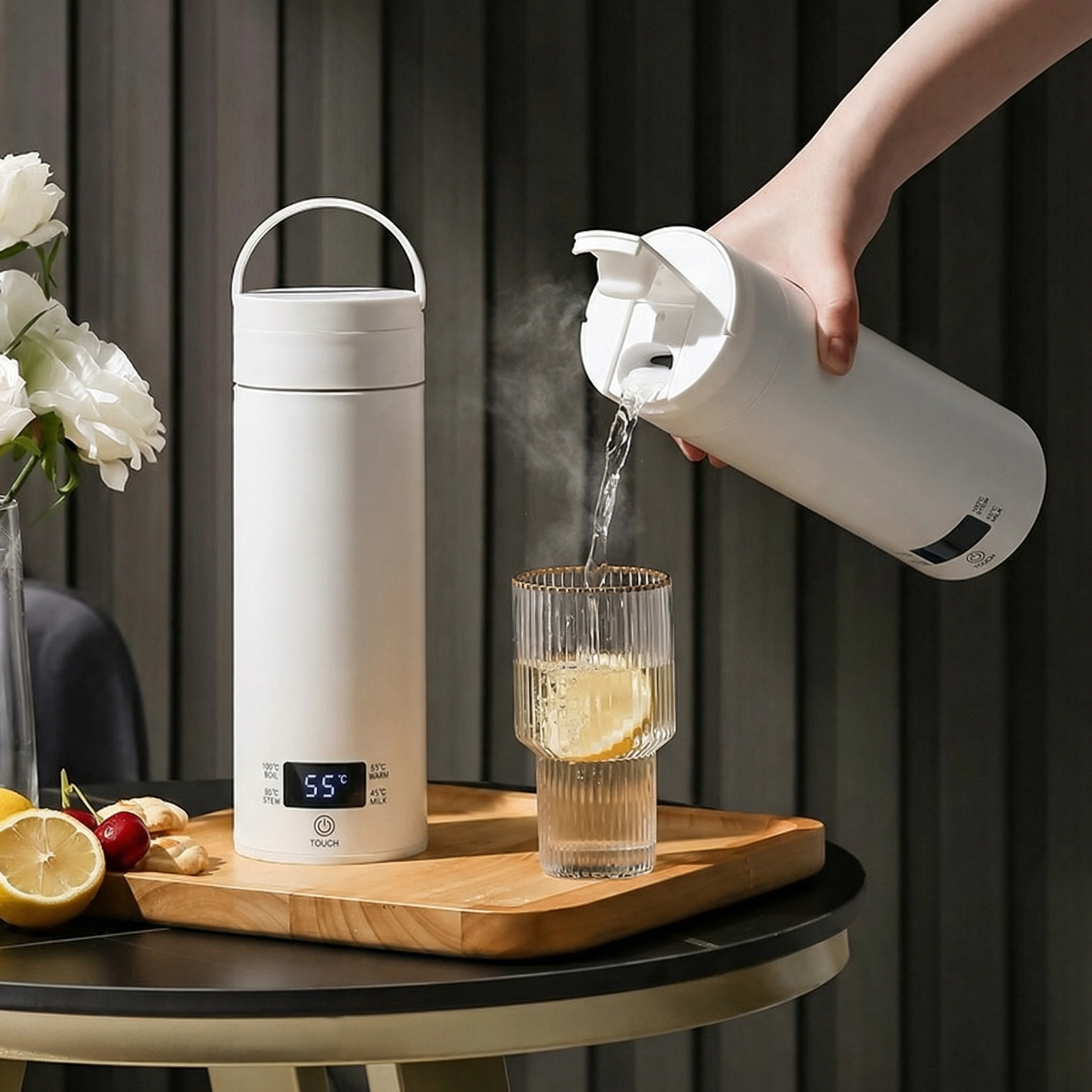 White electric kettle being used to pour water into a glass on a wooden tray.