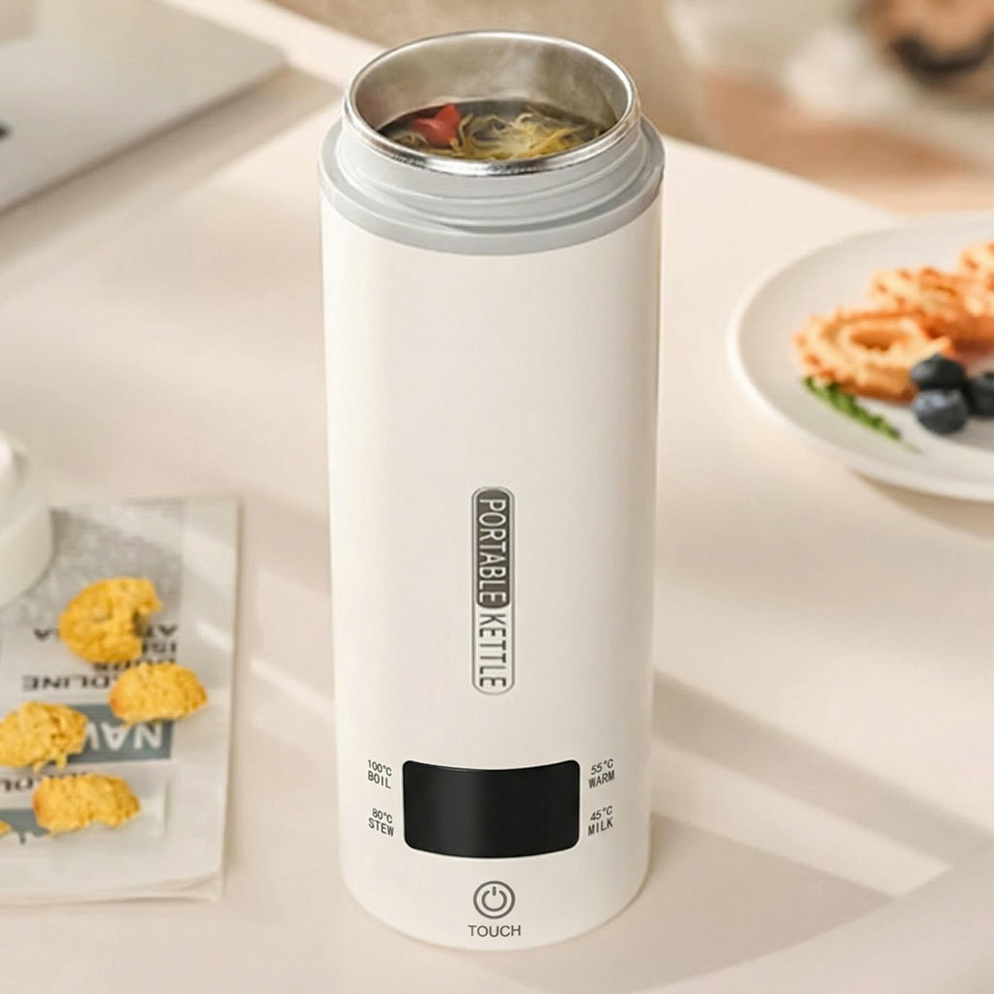 White portable kettle on a table with food items in the background