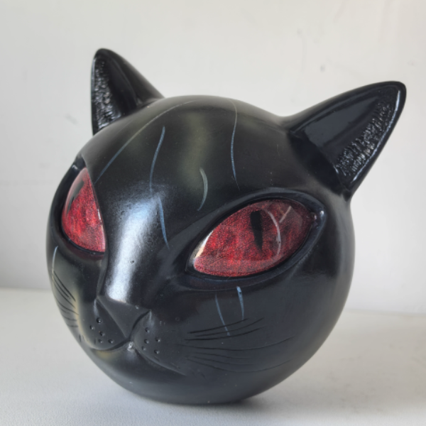 Black cat-shaped object with red eyes on a white background