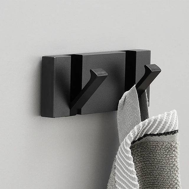 Black wall hook with a towel on a light gray background