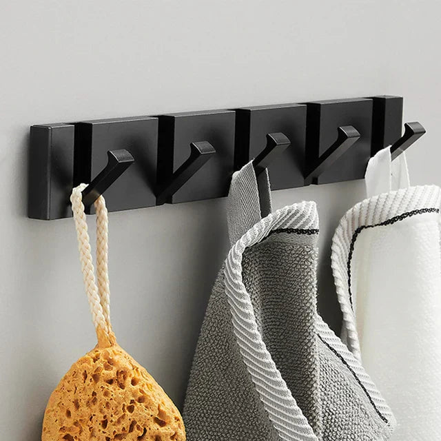 Black wall-mounted hook rack with various items hanging on it against a gray background