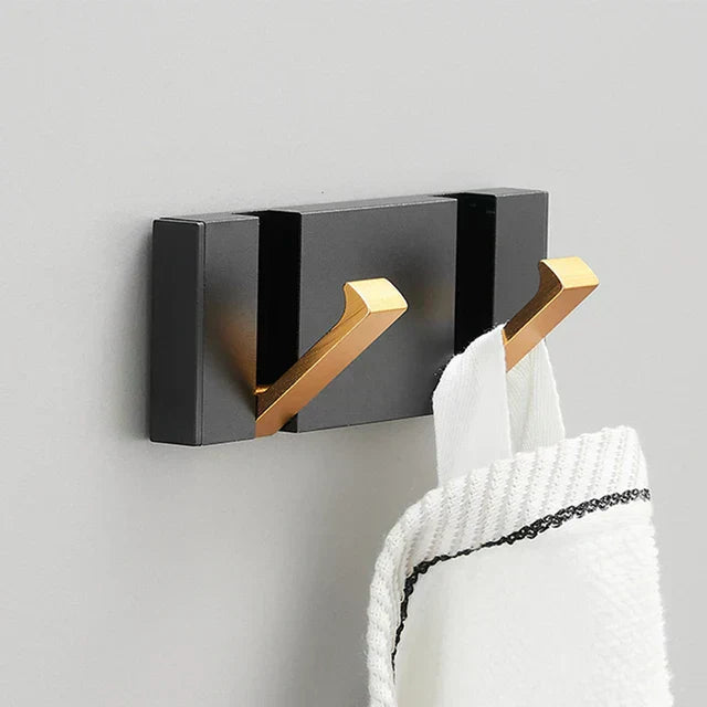 Black and gold wall hook with a white towel on a gray background