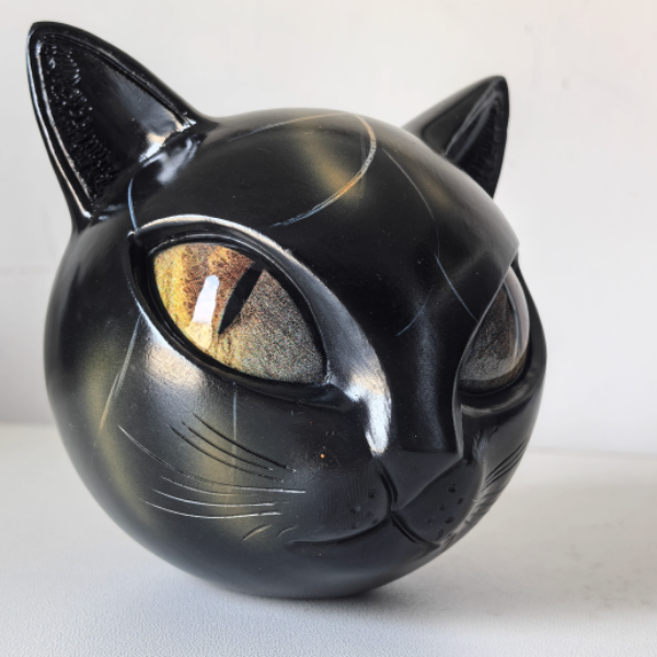 Black cat-shaped object with glowing eyes on a white background