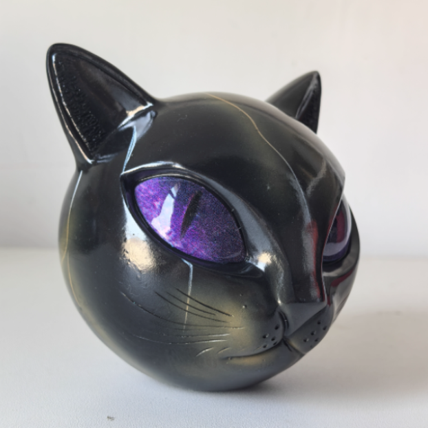 Black cat-shaped object with purple eyes on a white background