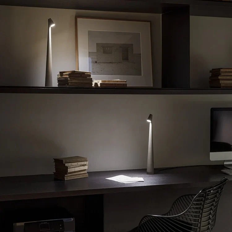 Dark office desk with lamp, books, and computer monitor in a dimly lit room.