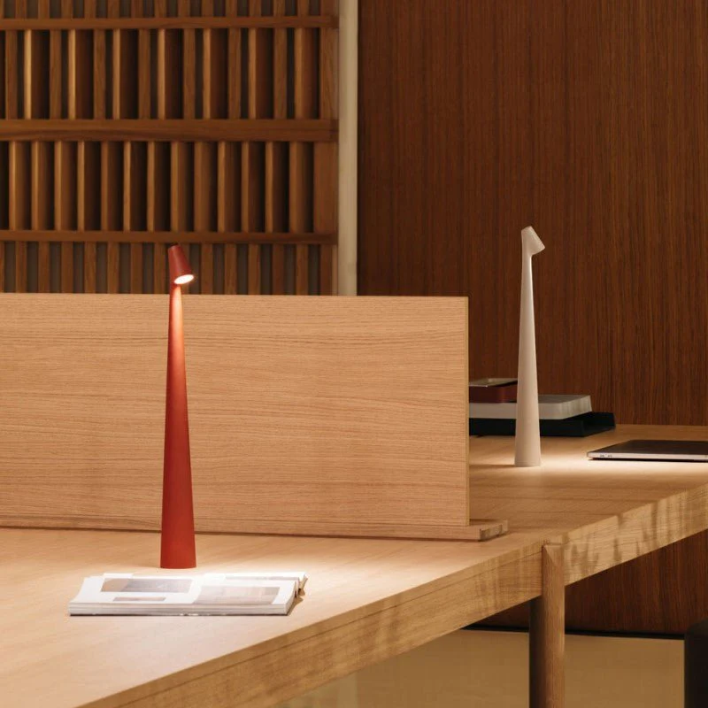 Red table lamp on a wooden desk with a minimalistic background